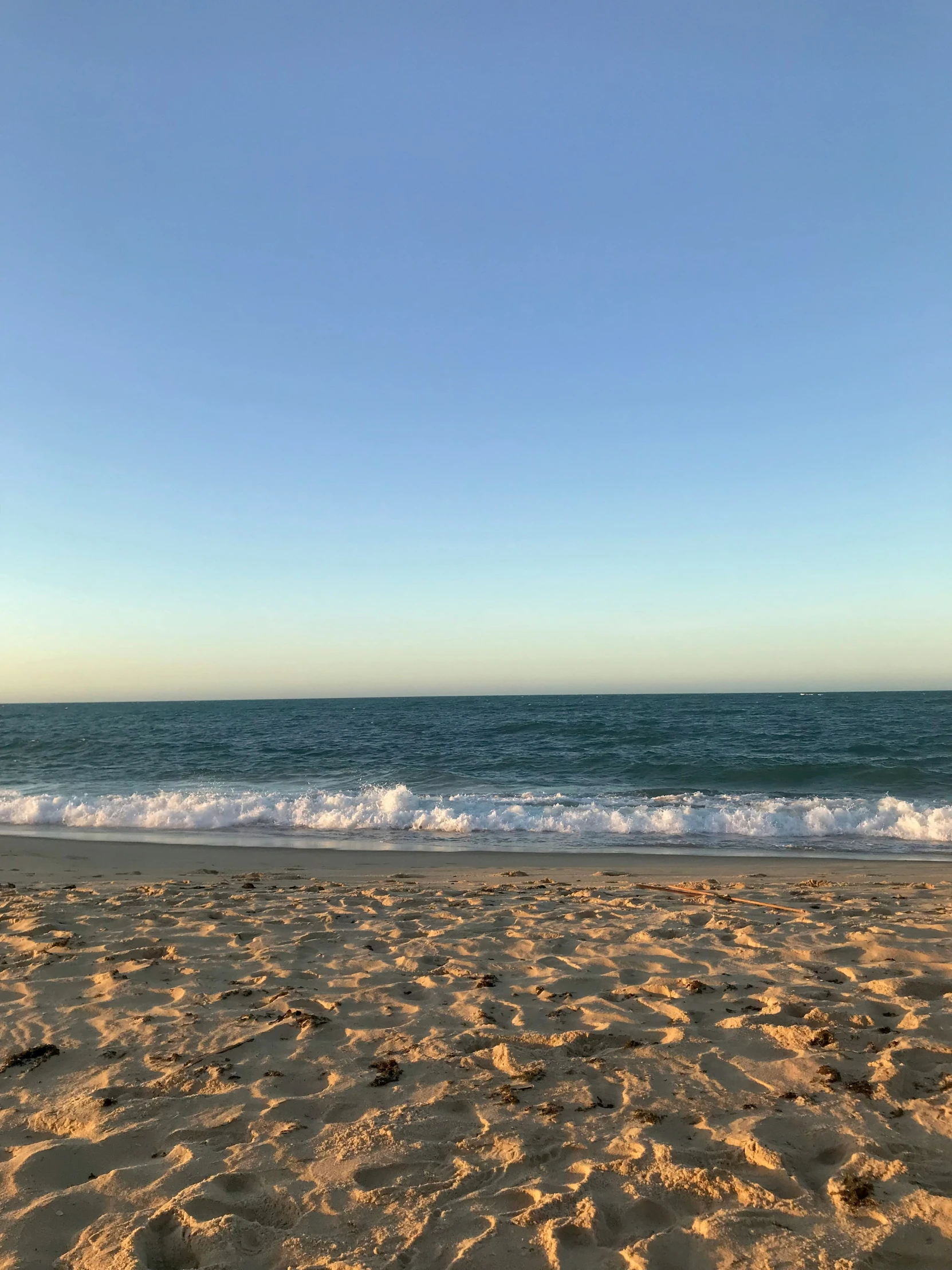 the sky and water at a beach with footprints in sand