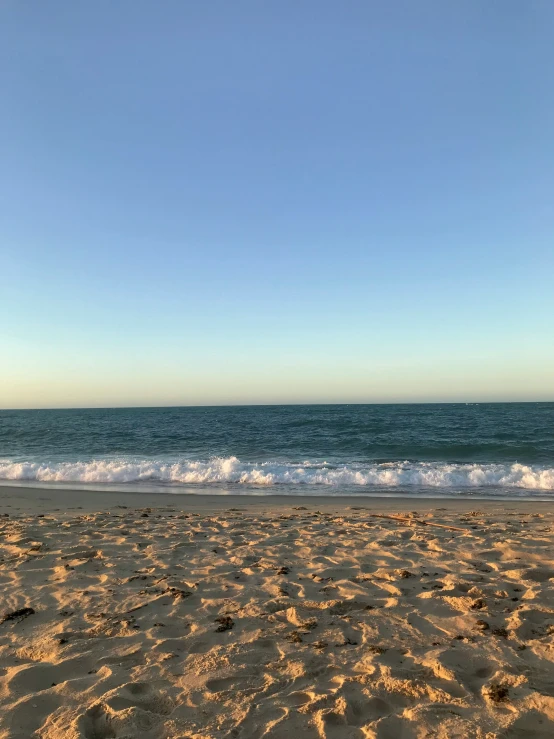 the sky and water at a beach with footprints in sand