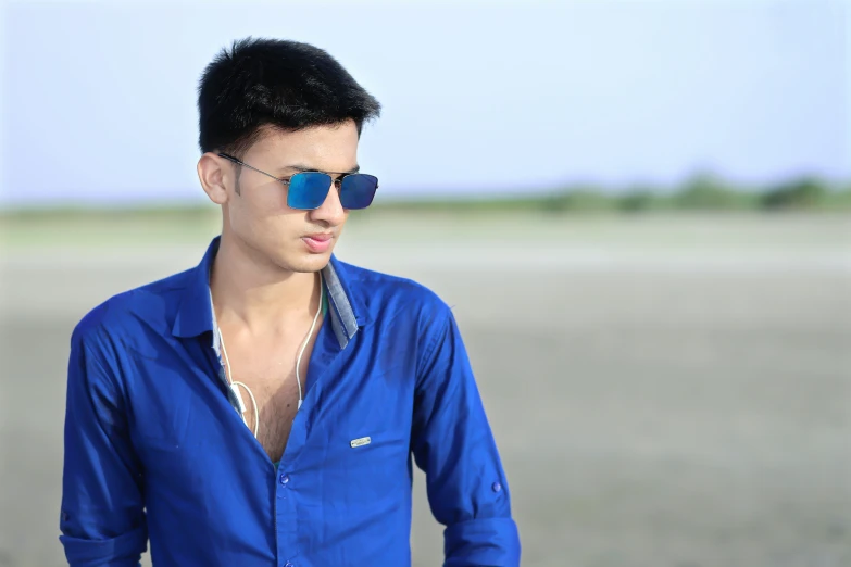 a man in a blue shirt wearing sunglasses looking away