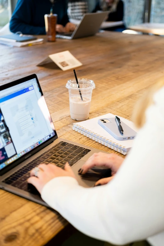 people sit at a table in an office with a laptop and coffee