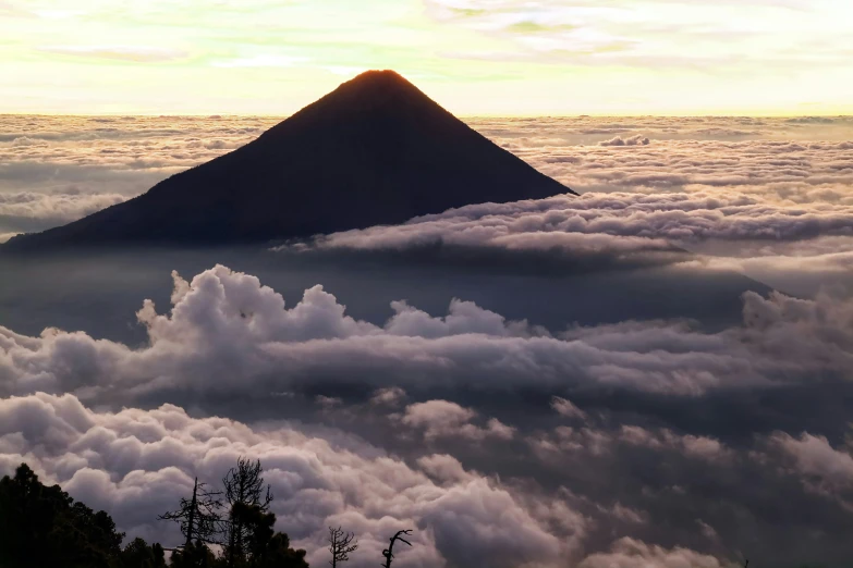 a very big mountain in the clouds with a cloudy sky