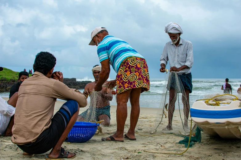 several men on the beach with fishing nets and a boat