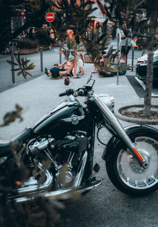 a motorcycle parked in front of a tree with people laying on the ground