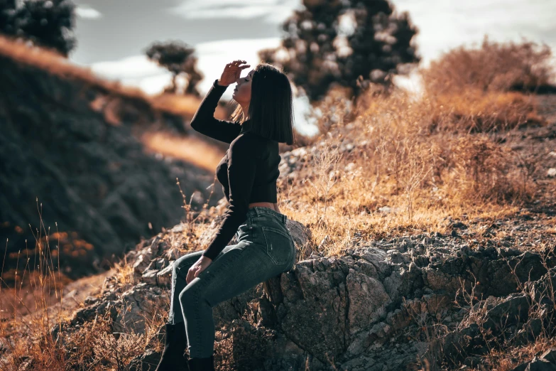 a woman sitting on a stone wall looking at the sky