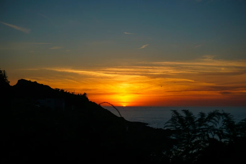 a dark and colorful sky over the ocean