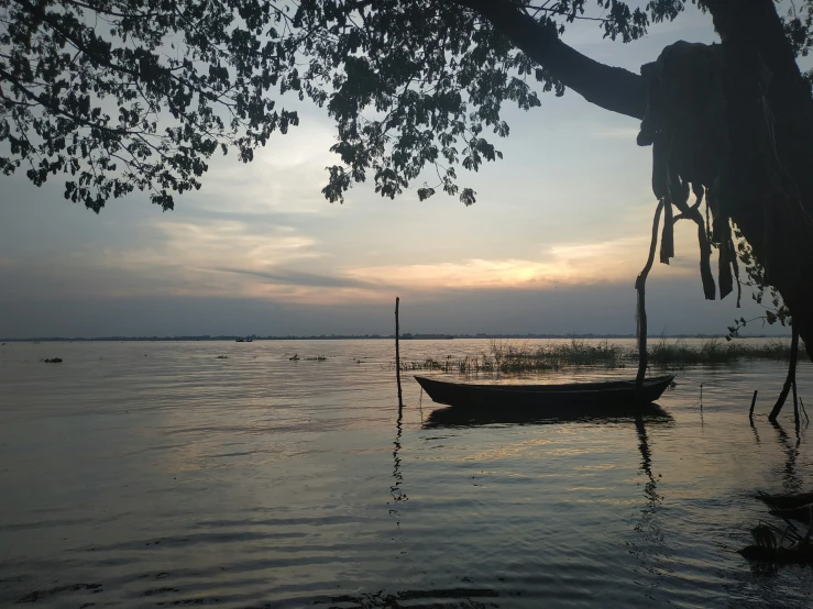 a boat sitting on the water at sunset