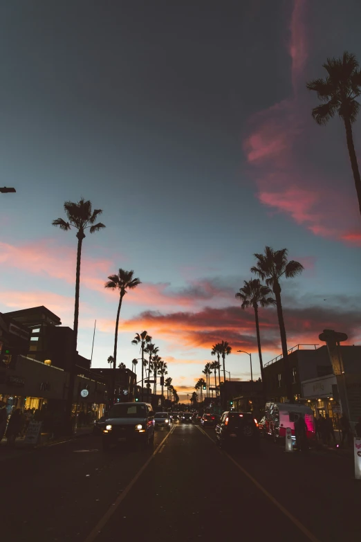 a street filled with cars under a pink sunset