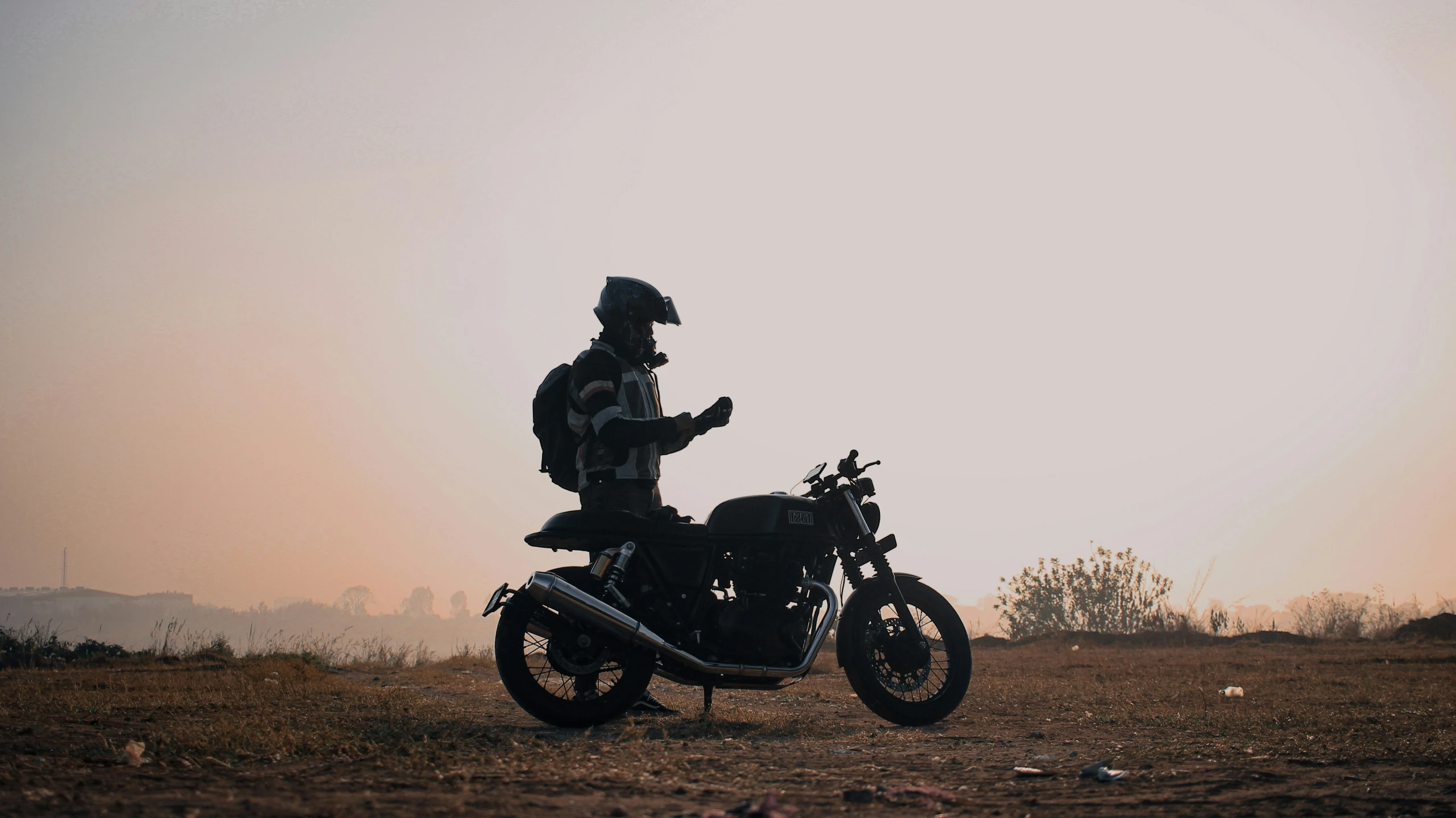 silhouette of man on motorcycle looking at cellphone