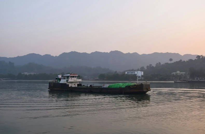 a boat traveling in calm water next to hills