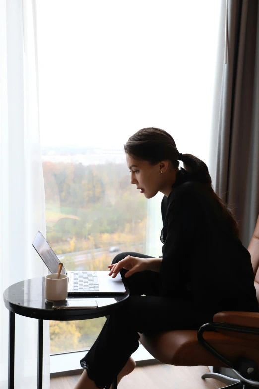 a young woman using a laptop and writing on a paper