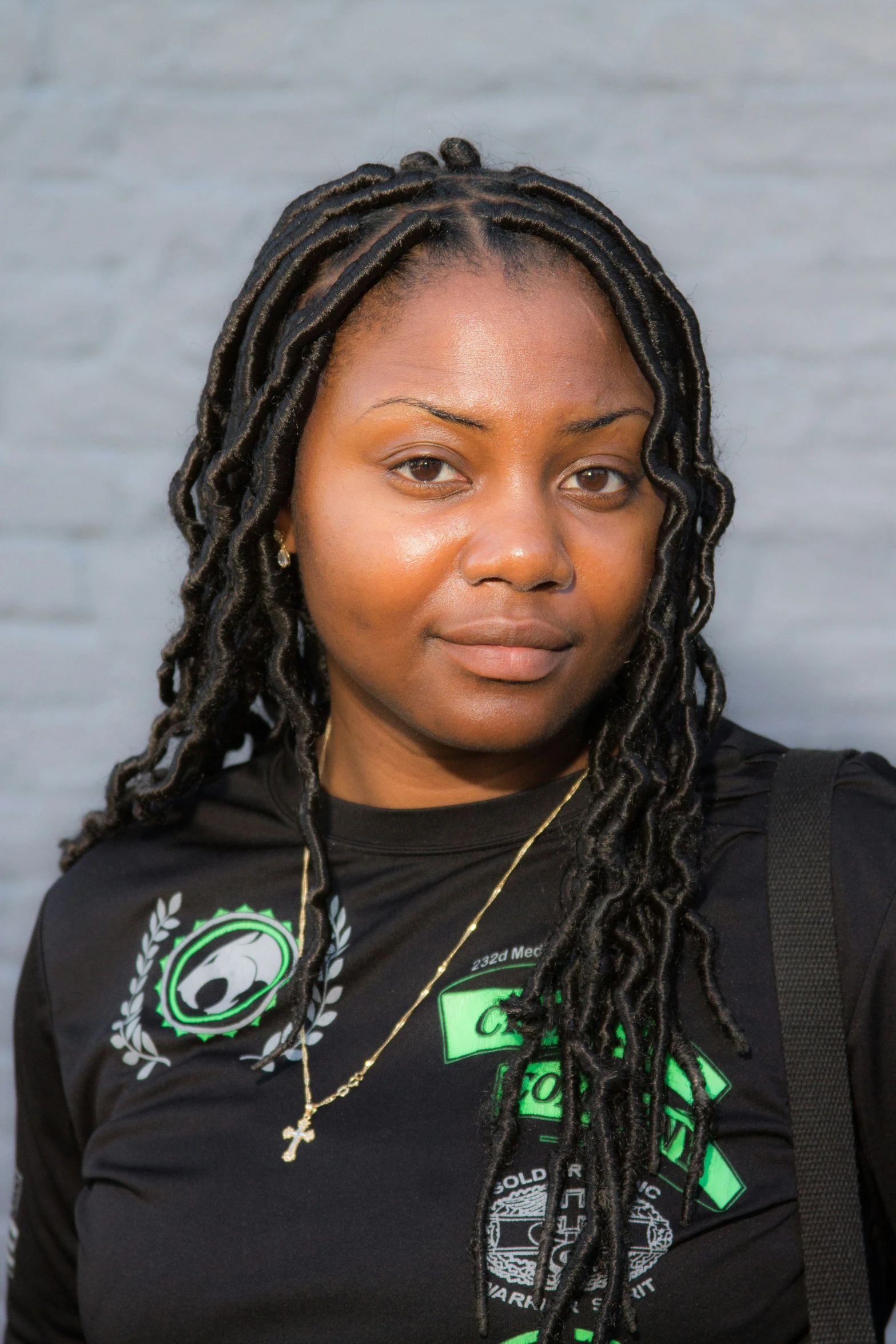 woman with dread locks and shirt against a wall