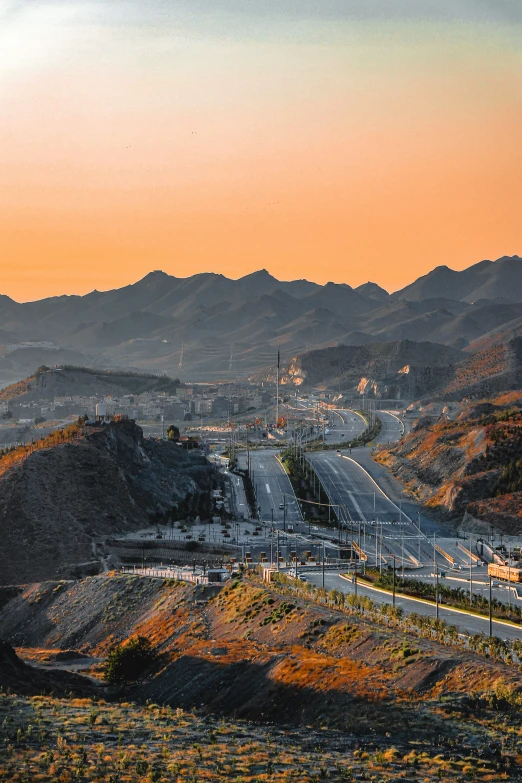 a view of the sun setting behind a city with mountains in the background