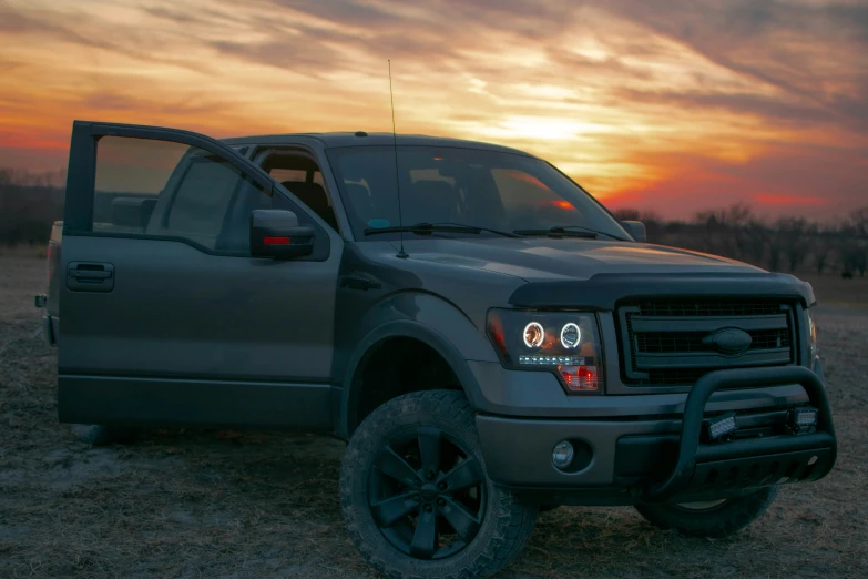 the truck is sitting in the grass at sunset