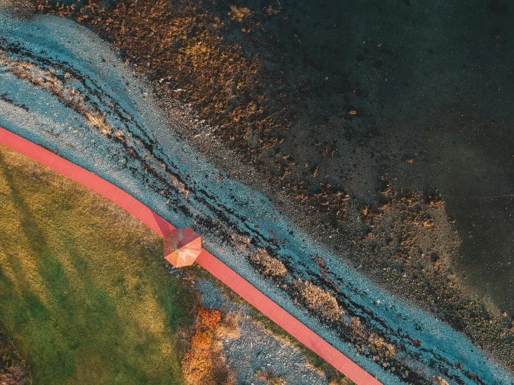 an aerial view shows patches of ice and grass near the river's edge