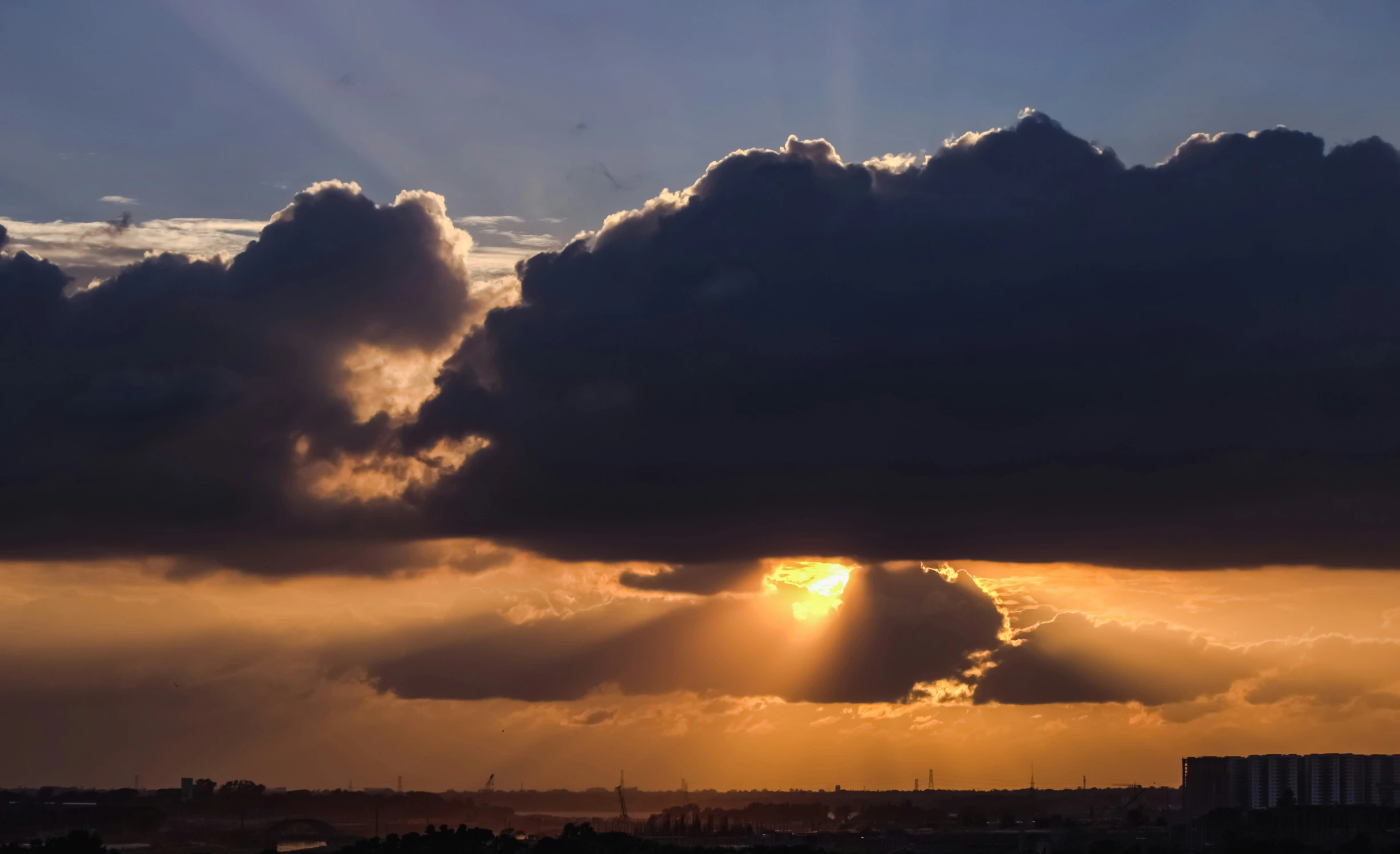 a sunset with a huge cloud and the sun peeking out of the middle of the clouds