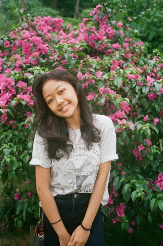 a person standing next to bushes with pink flowers