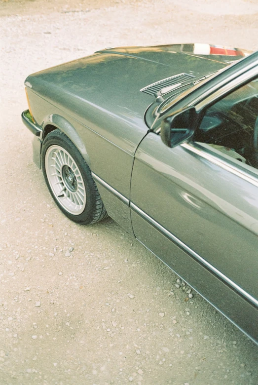 a gray sports car is parked on a dirt road