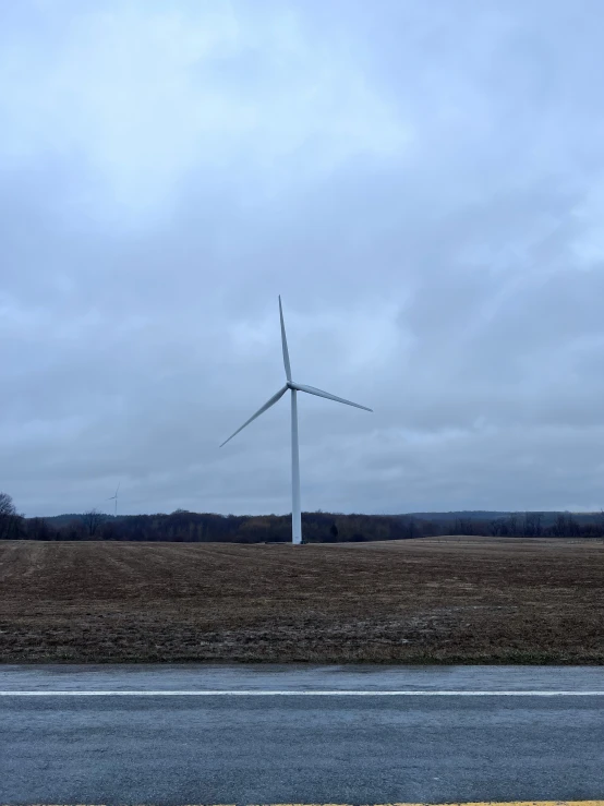 wind turbine with large white blades against a cloudy sky