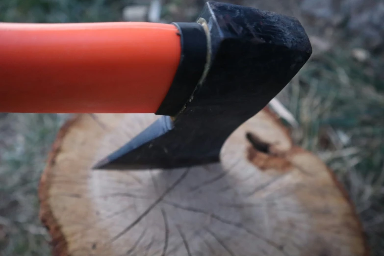 an orange handled knife resting in a cut wood