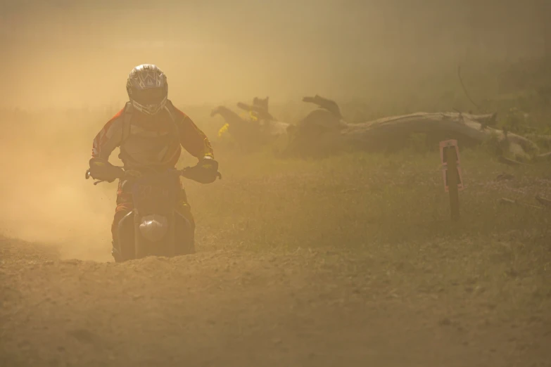 a man riding on the back of a motorcycle down a dirt road