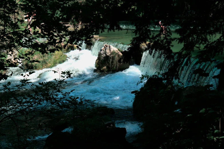 the sun shines on a waterfall through trees