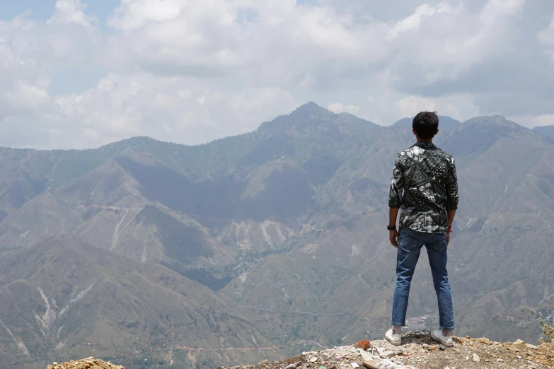 a man stands on top of a mountain looking at mountains