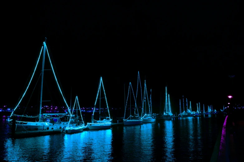 lots of boats in the water lit up with christmas lights