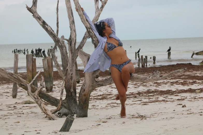 a woman in bikini and a scarf standing on a beach