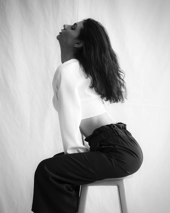 a beautiful young woman sitting on a stool