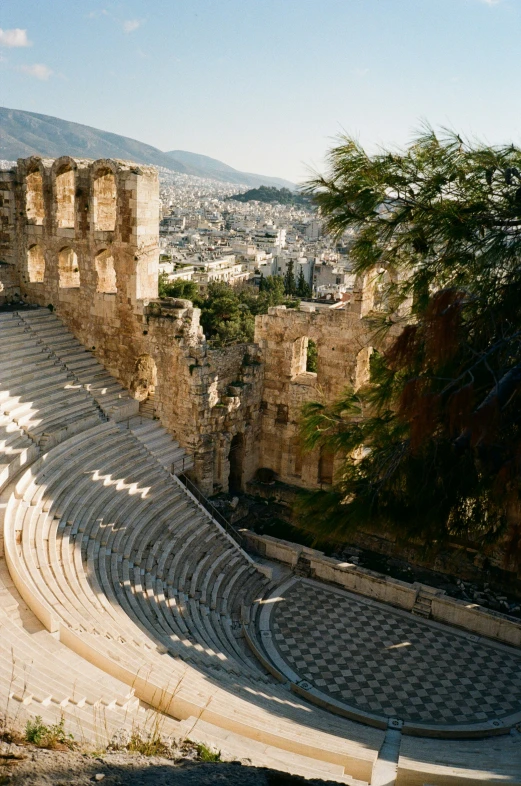 an outdoor theater with a stone floor next to the city