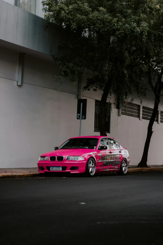 a pink bmw parked in front of a tree