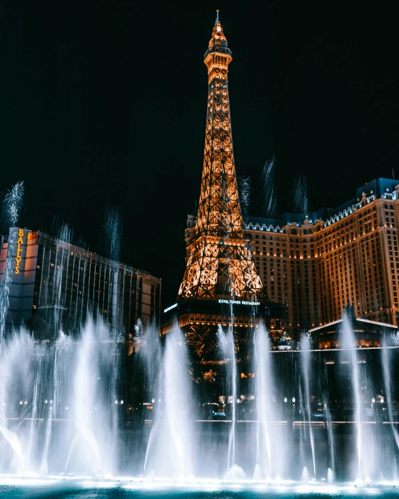 the illuminated tower is in front of a fountain