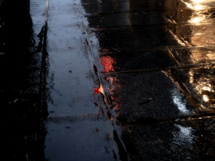 wet pavement with red paint on it and traffic cones at night