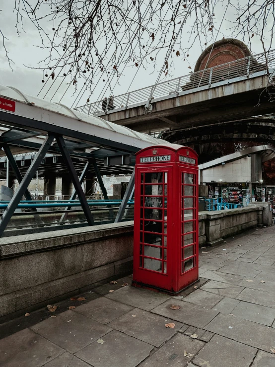 there is a red phone booth on the sidewalk