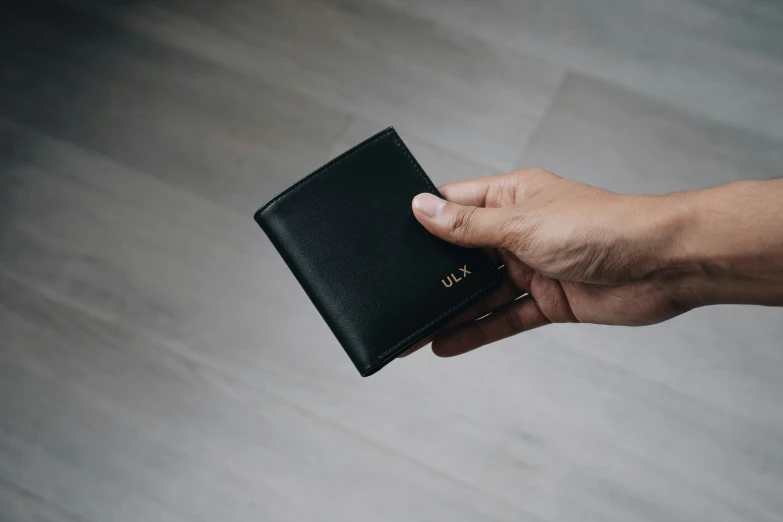 a hand holding a black small wallet