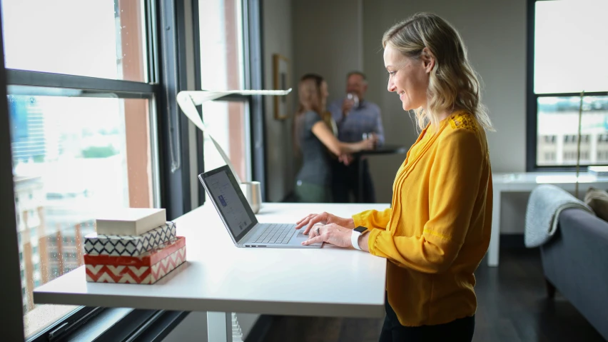 a person standing near a window with a laptop