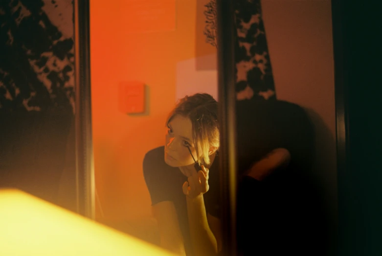 young woman with short hair using cell phone in mirror