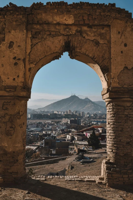 an arch above a city below a mountain