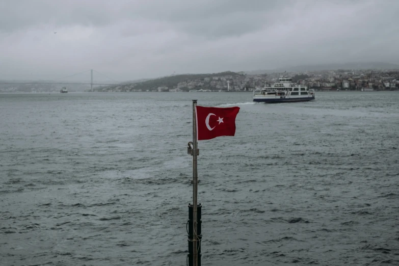 flag of turkey flying high in the wind next to the ocean