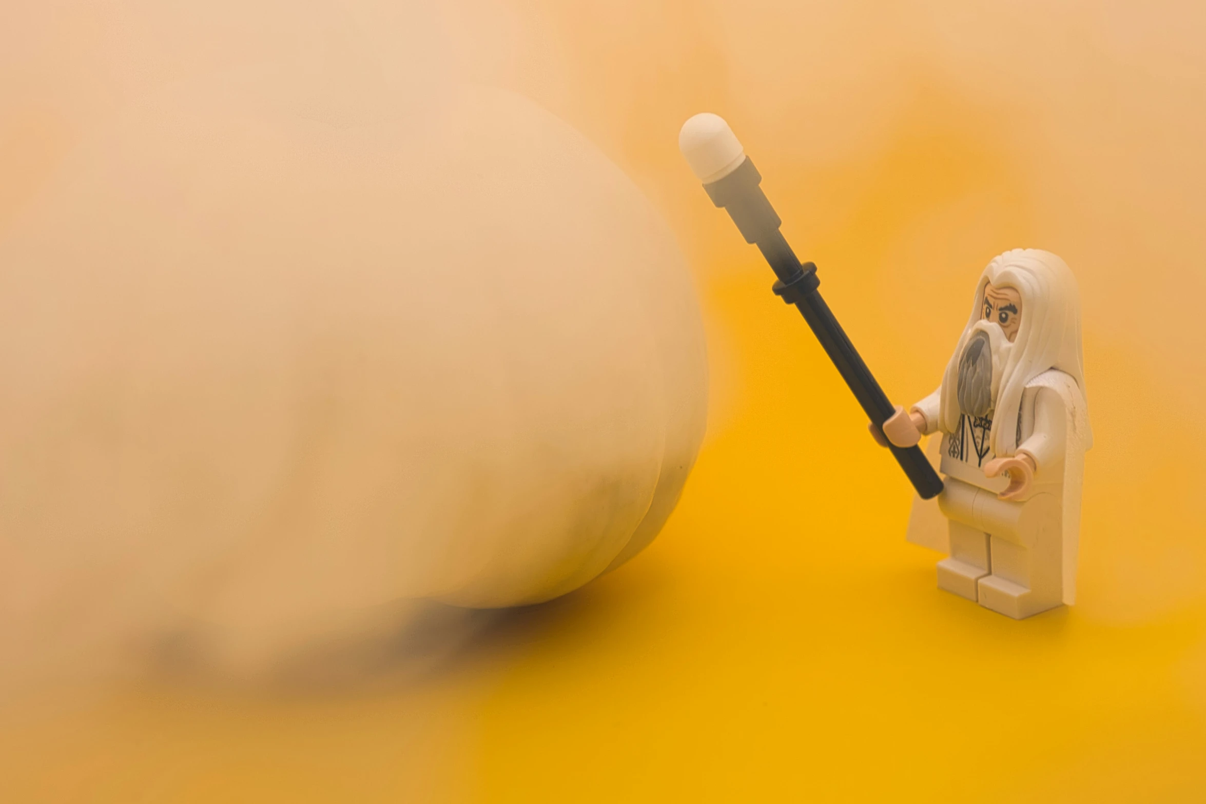 small lego man standing next to a large ball