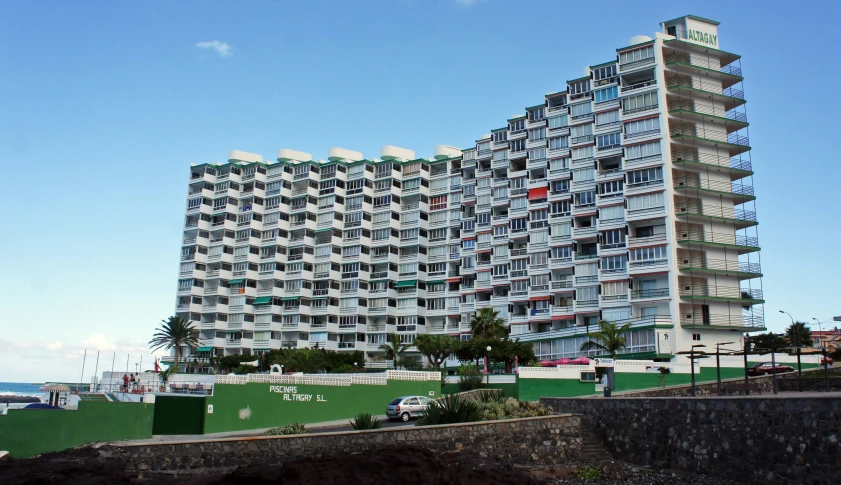 a tall building next to the ocean with apartments built on top