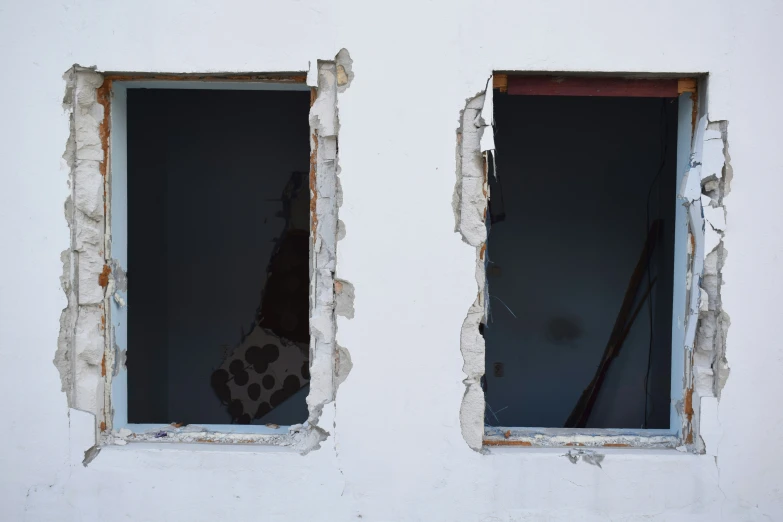 a broken window showing two panes of glass and old rust