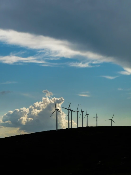 a row of wind mills on the top of a hill