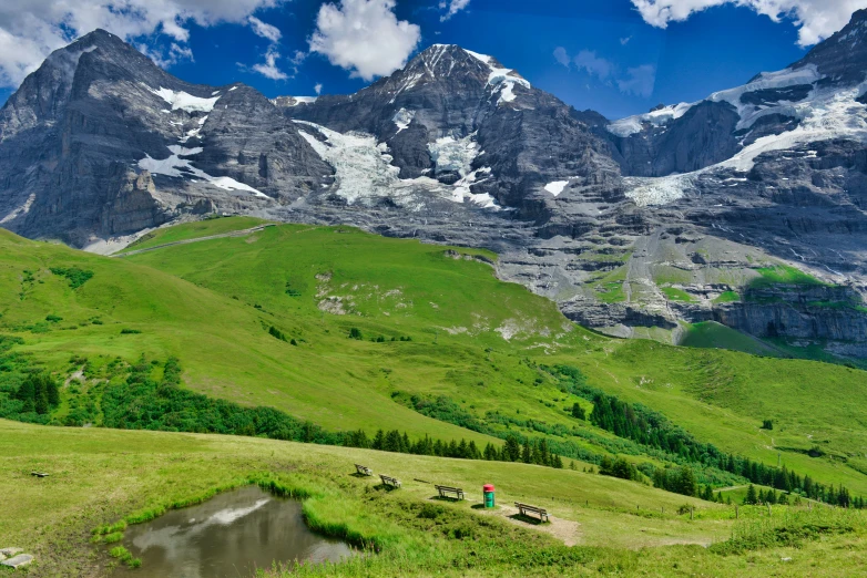 two horses graze in the green grass below a mountain range