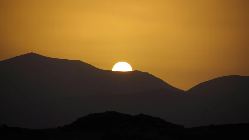 the sun is setting in the sky over mountains