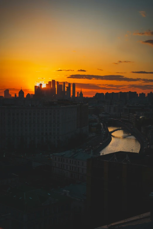 an orange sunset and water and buildings near a river