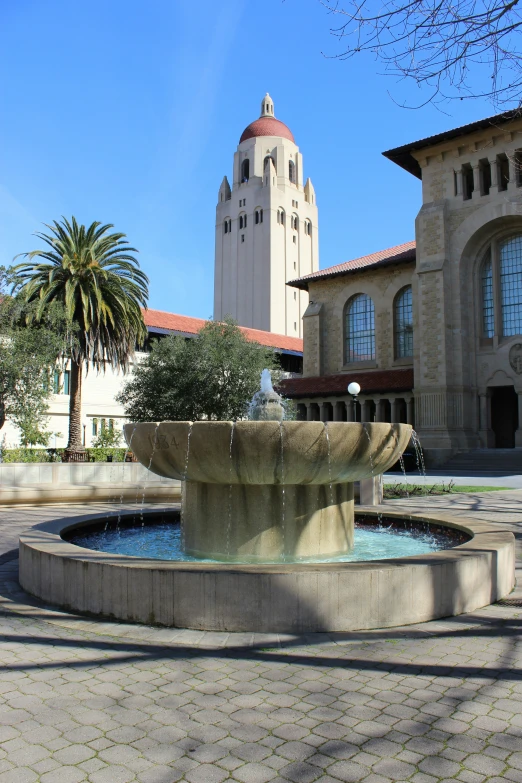 a small fountain in front of a building and a tower