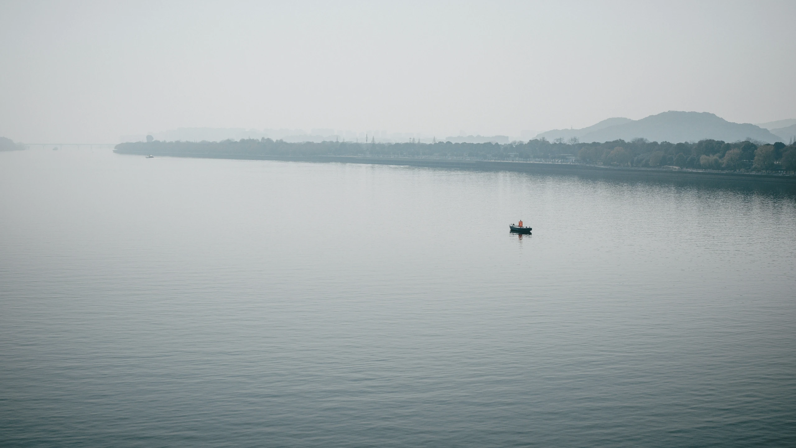 a boat on a calm lake with mountains in the background