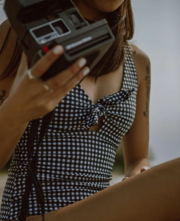 a women with tattoo holds an old camera