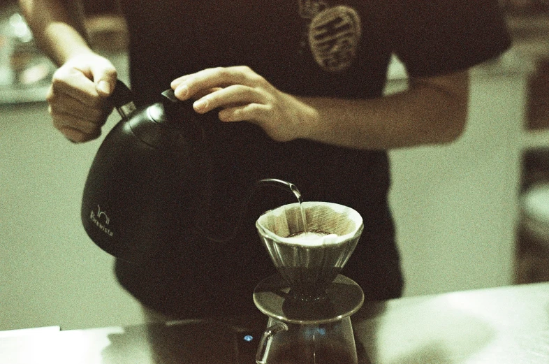 person pouring coffee into glass carafe, making espresso